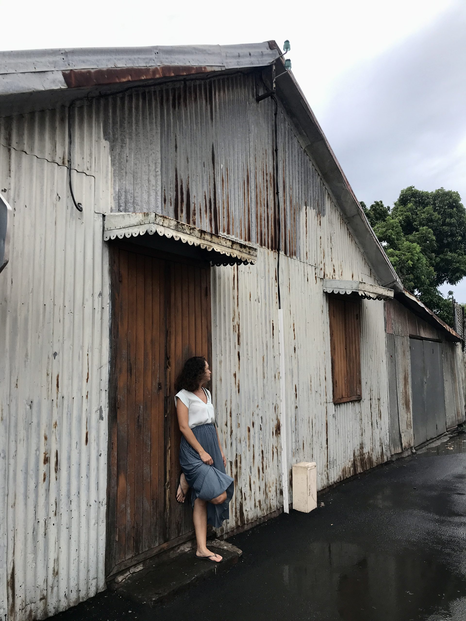 Ophélie Brodelle Maillot adossé à un entrepôt regardant au loin